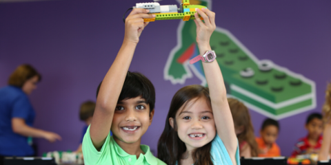 Two children hold up a lego toy they built together