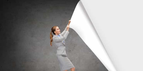 a business woman pulls at a large sheet of wallpaper