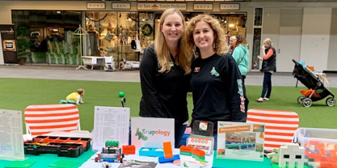 Shannon and a woman smile at a snapology table