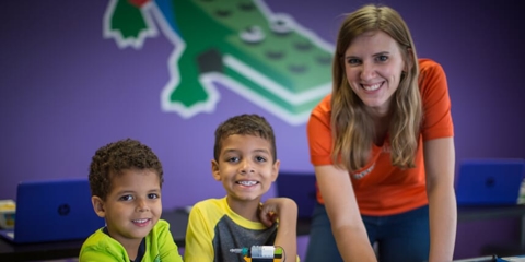 franchisee smiling with two boys playing with robotics