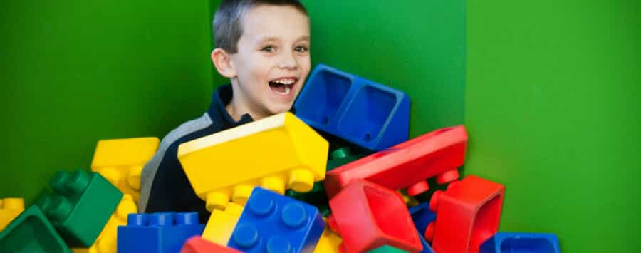 A young boy sits among giant Lego blocks