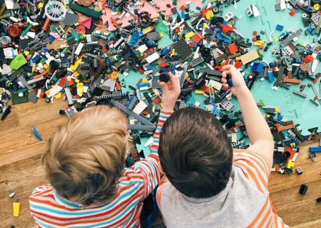 Two young boys play with a large amount of Legos on the floor