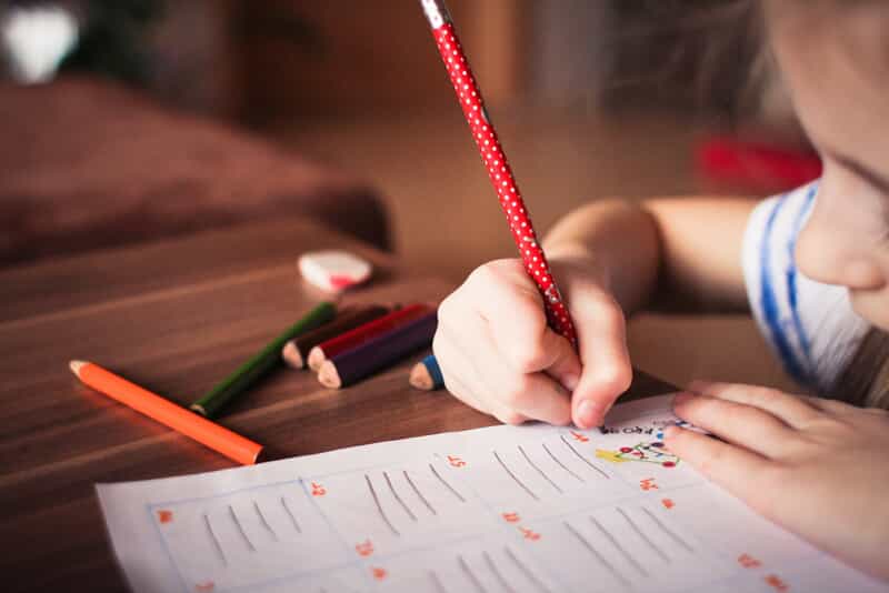 a young girl colors on a sheet of paper