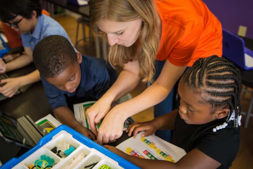 a snapology team member helps young kids build something from legos