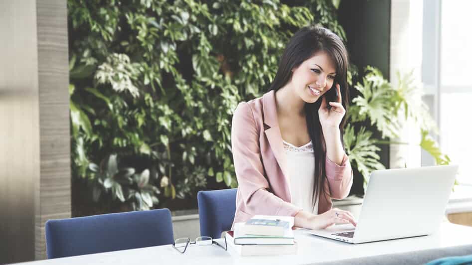 a woman speaks on the phone while browsing her computer