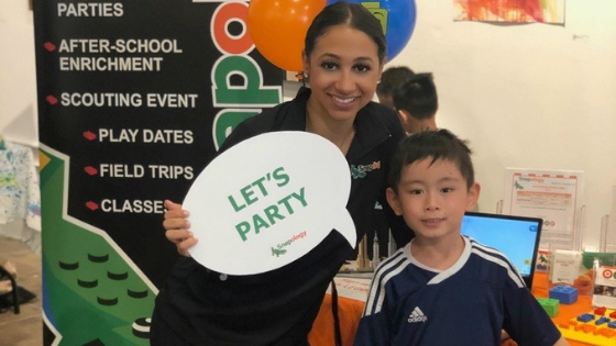 Jessica smiles with a child and a sign saying "Lets Party"
