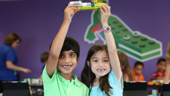 Two children hold up a lego toy they built together