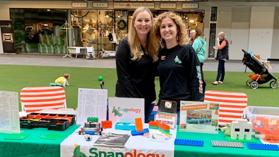 Shannon and a woman smile at a snapology table