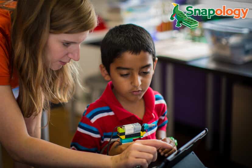 a child and an instructor build a contraption while looking at a tablet